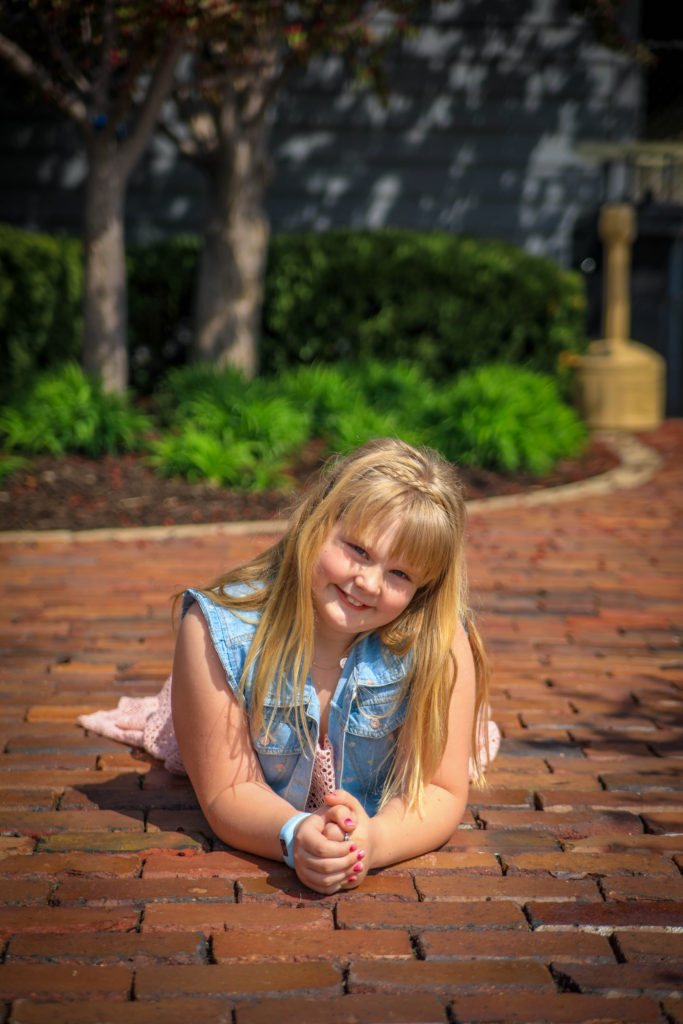 Elizabeth laying on the brick ground with vest and pink dress