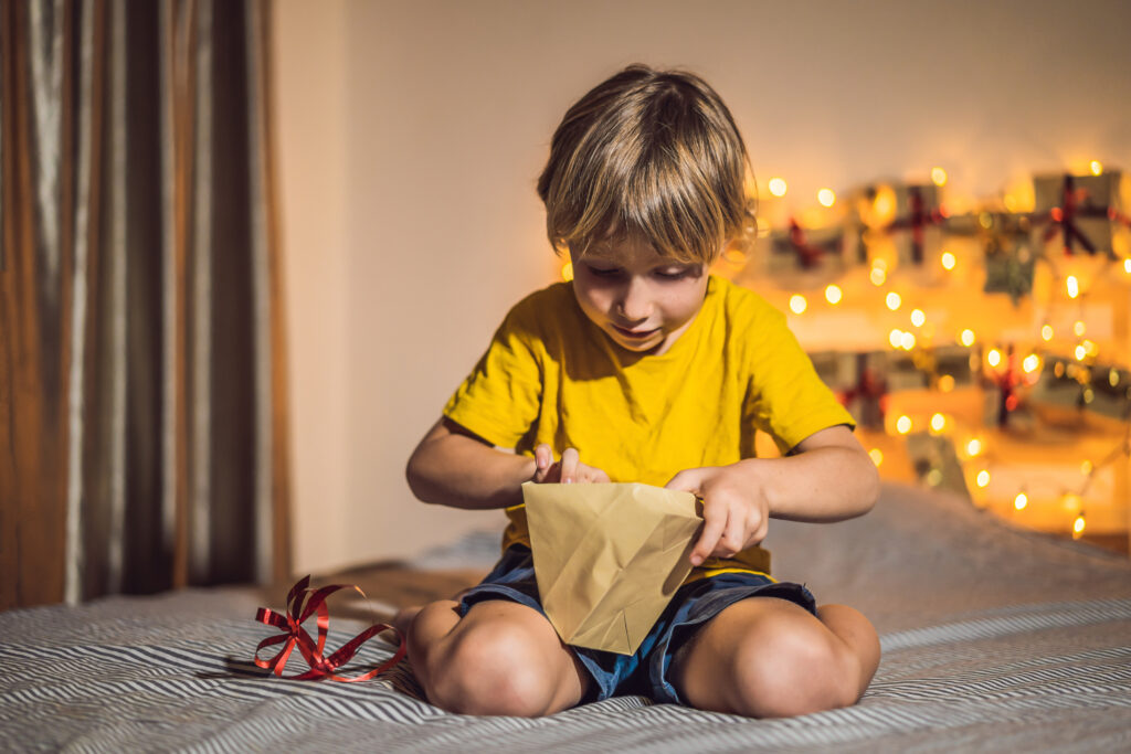 a boy opening a advent calendar bag sitting on a ottemn