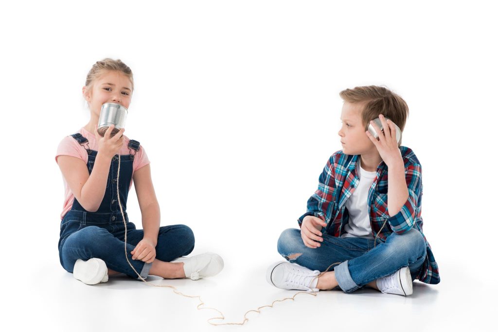 young boy and girl talking on a tin can phone